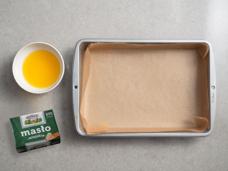forma do ciasta wyłożona papierem obok masło