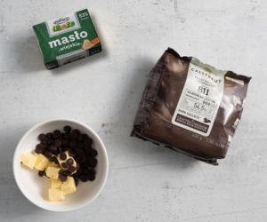 Na blacie kuchennym kostka masła oraz czekolada w miseczce.