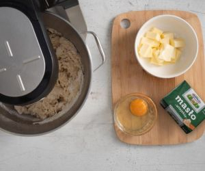 W misie miksera zagniatanie ciasta drożdżowego. Obok na desce miękkie masło oraz jajko.