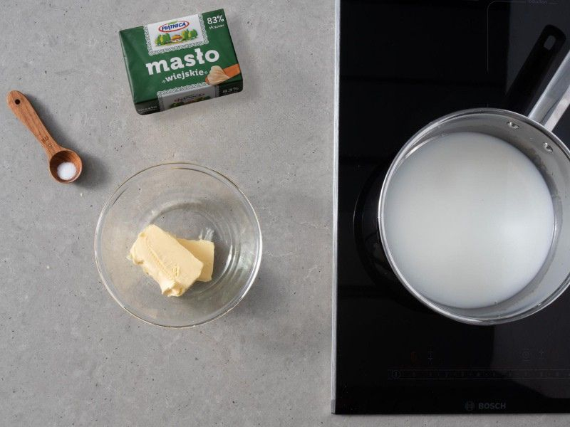Na blacie garnek z wodą, mlekiem,solą i masłem.