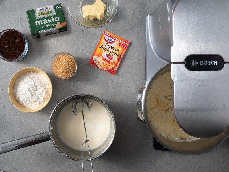 w misie robota ubite jajka z cukrem obok składniki na ciasto kakaowe, masło i proszek do pieczenia dr. oetkera