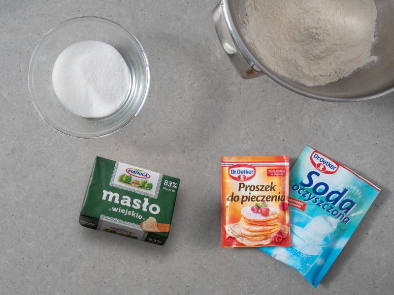 W misie miksera mąka. Obok soda oczyszczona Dr. Oetkera, proszek do pieczenia, oraz masło.