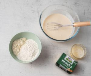 w miskach mokre i suche składniki na proteinowe gofry i roztopione masło w szklanej miseczce