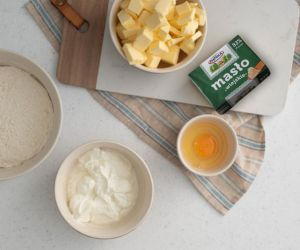 W miseczce twaróg, jajko. Obok masło pokrojone w kostkę.