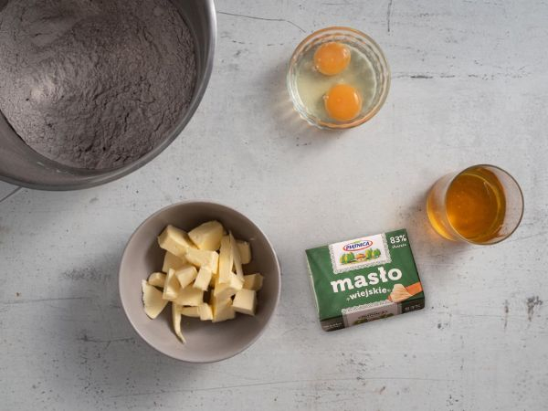 Na blacie kuchennym składniki do pierniczków (masło, miód oraz jajka)