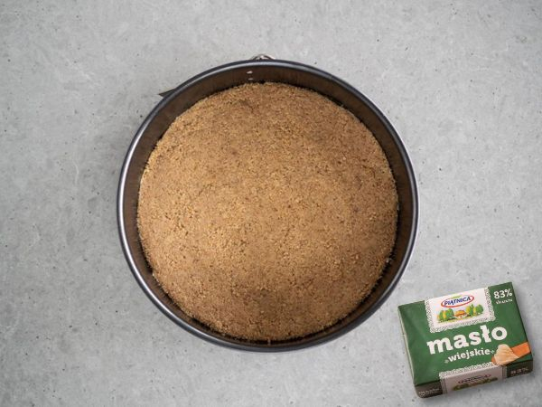 pokruszone herbatniki z masłem, cynamonem na dnie tortownicy