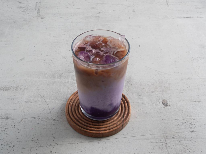Gotowe iced ube late na drewnianej podstawce.