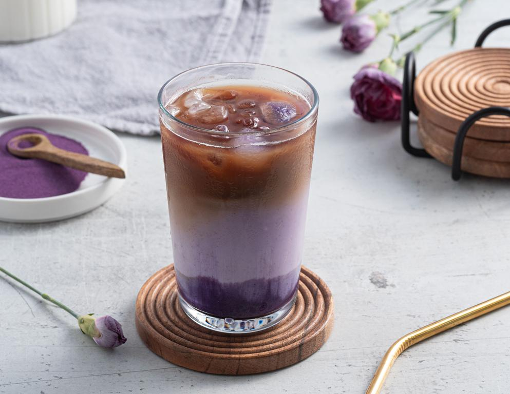 Iced Ube Latte z kawą i kostkami lodu w wysokiej szklance na drewnianej podstawce - Wszystkiego Słodkiego
