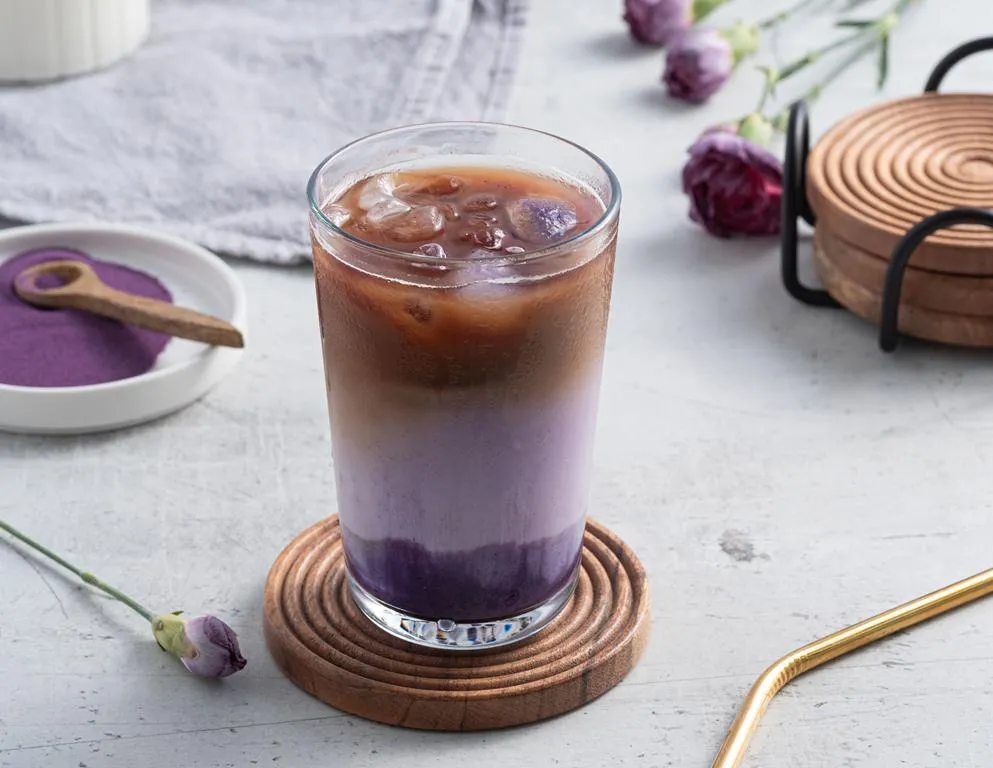 Iced Ube Latte z kawą i kostkami lodu w wysokiej szklance na drewnianej podstawce - Wszystkiego Słodkiego