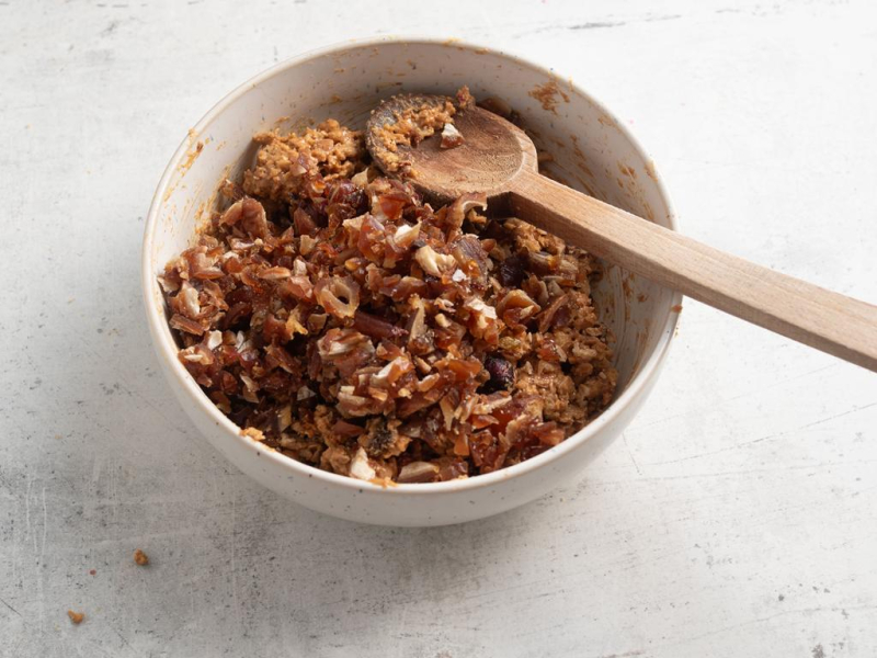 Granola wymieszana w miseczce z masłem orzechowym.