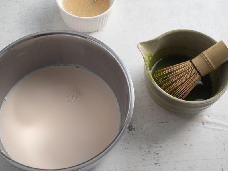 W garnku napój migdałowy. Obok rozrobiona herbata matcha.