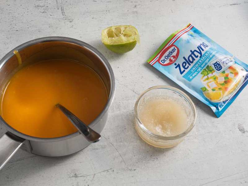 W garnku pulpa z mango. Obok opakowanie żelatyny i żelatyna w szklanej miseczce.
