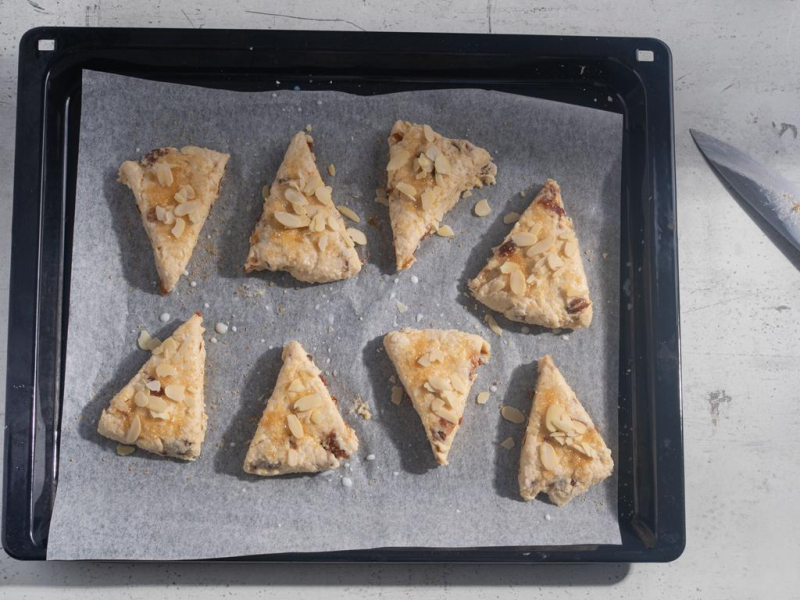 Scones przed pieczenia posmarowane mlekiem, cukrem i płatkami migdałów.