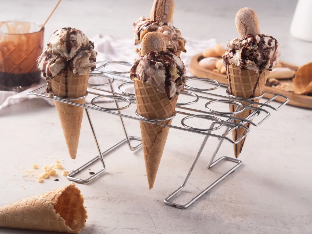 lody tiramisu w wafelkach, oblane syropem kawowym, na stojaku na lody