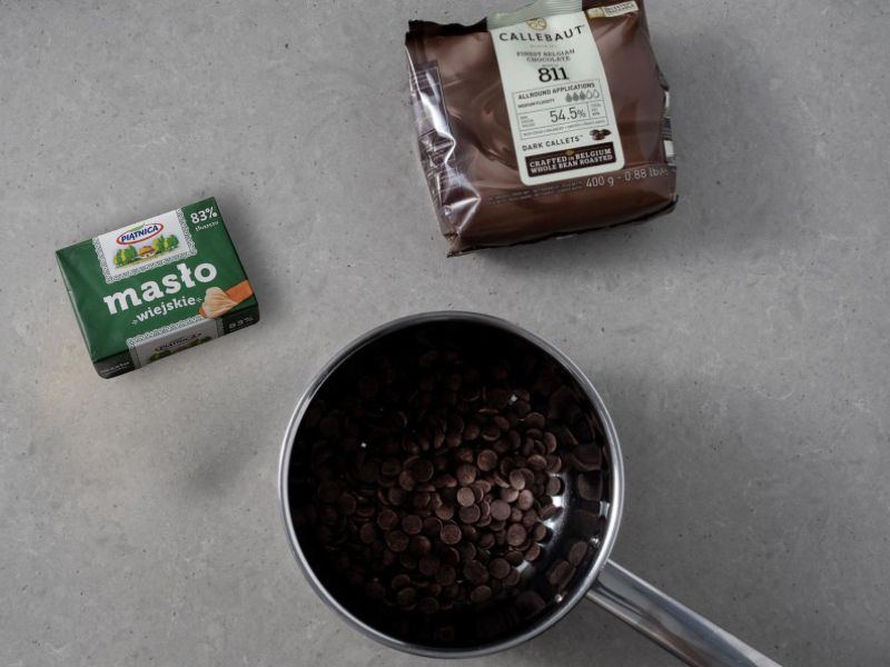 na blacie masło i w garnku czekolada Callebaut w kaletkach
