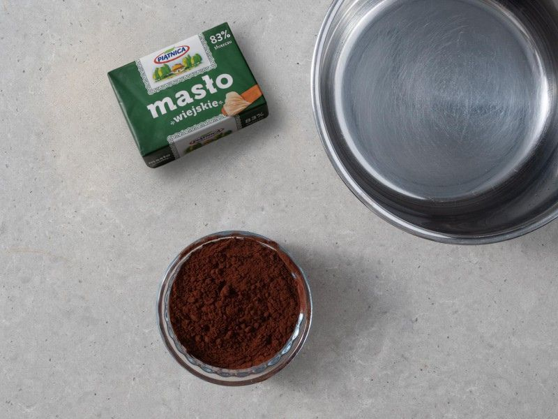 w rondelku składniki na masę czekoladową obok masło