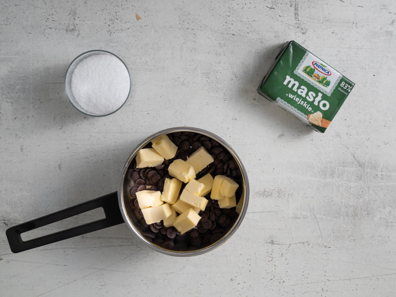 w garnku czekolada z masłem, obok ksylitol oraz kostka masła