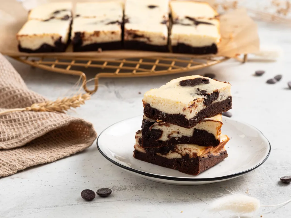 Proteinowe sernikobrownie ze skyrem i odżywką białkową. Kawałki sernikobrownie pokrojone na talerzyku - przepis Wszystkiego Słodkiego