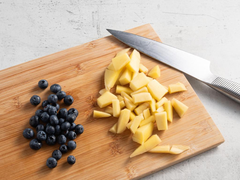 Świeże owoce mango i borówki na drewnianej desce.