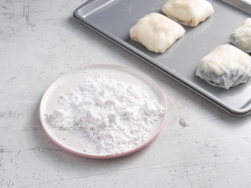 Na talerzyku mąka ziemniaczana, a obok na tacce zawinięte mochi.