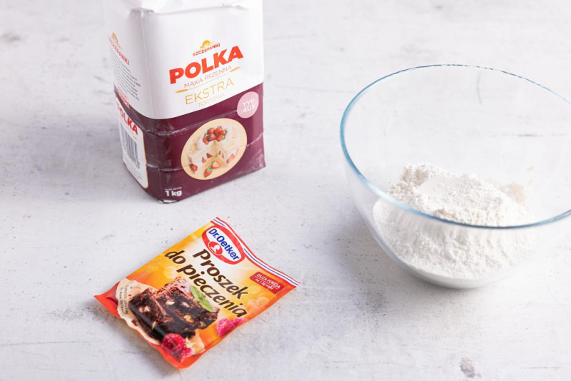 Na blacie kuchennym proszek do pieczenia, mąka i miseczka.