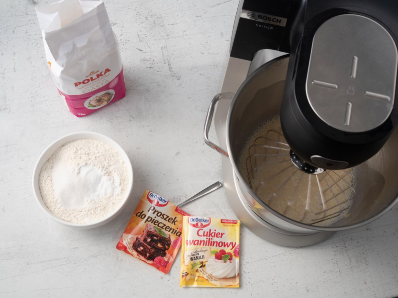 na blacie proszek do pieczenia z cukrem wanilinowym obok robot z ciastem na gofry