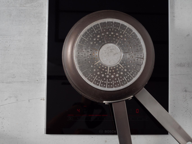 na małej kuchence indukcyjnej przykryta patelnia drugą patelnią