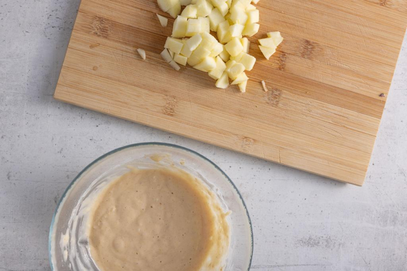 Pokrojone jabłka na desce, a obok masa na omlet.