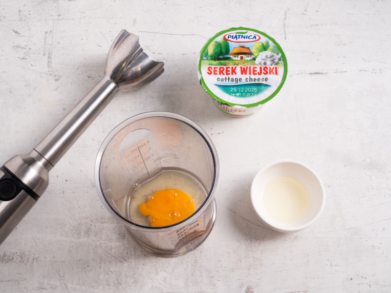 blender ręczny, obok serek wiejski, jajko i olej