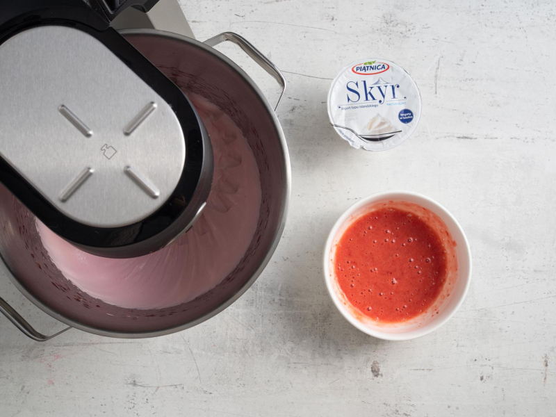 Ubita galaretka w misie miksera. Obok skyr oraz zblendowane truskawki.