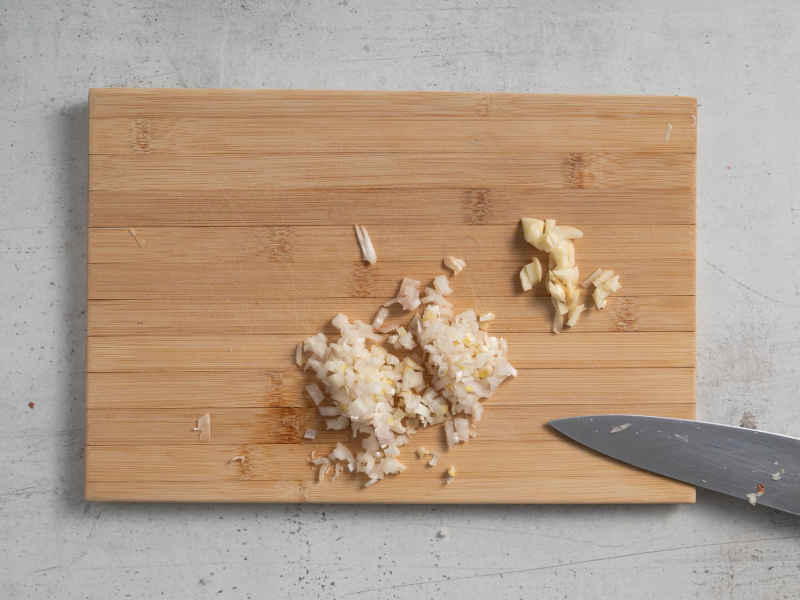 Pokrojony czosnek i cebula na drewnianej desce.