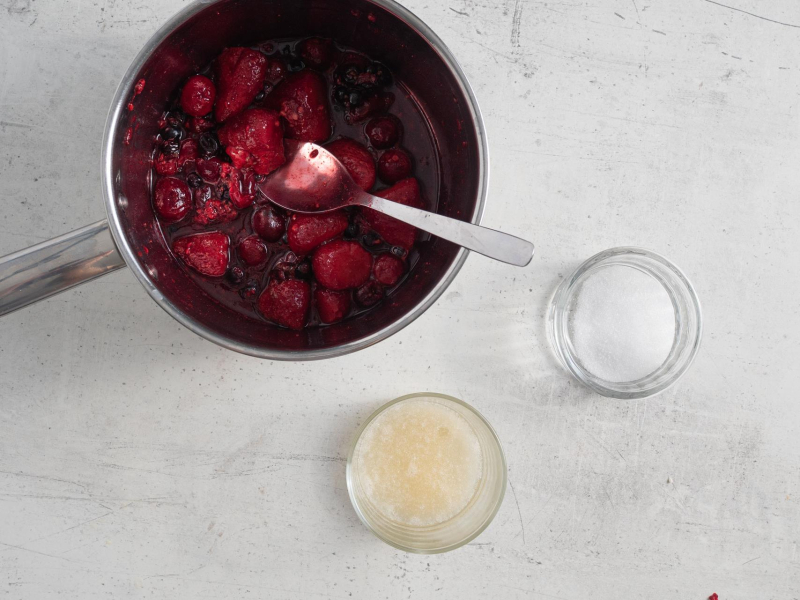 Mrożone owoce w garnku. Obok żelatyna w miseczce i erytrytol.