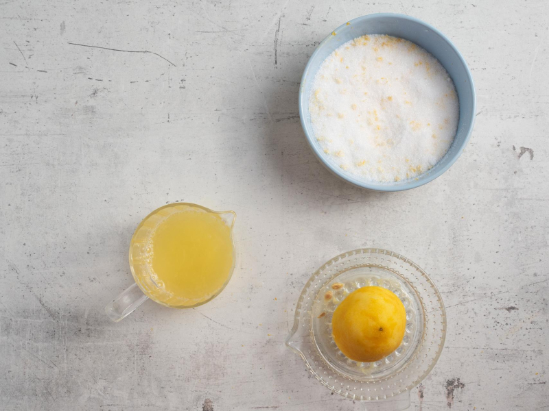 Na blacie kuchennym sok z cytryny oraz wyciskanie cytryny. Obok erytrytol.